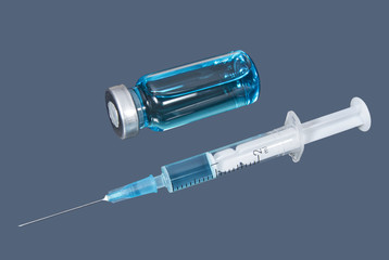 Syringe and phial with blue vaccine on the dark background