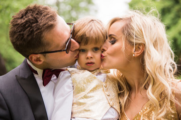 Close-up the happy family standing outdoor and parents  kissing their son