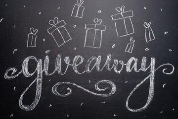 The inscription giveaway is written on a blackboard with gifts. Distribution of gifts. Blog,...
