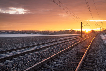 Obraz na płótnie Canvas Railway tracks through frozen nature at sunrise. Traveling context. Winter holiday travel.