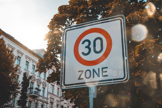 30 speed sign in a city street with sun flare
