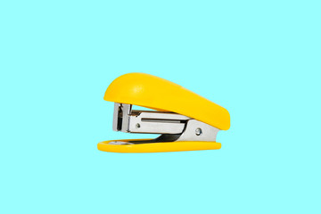 Yellow-colored stapler closeup on a blue background