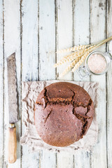 Fresh homemade traditional round rye bread on rustic wooden background, top view