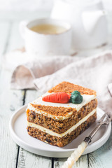 Slice of carrot cake with cream cheese frosting on wooden table