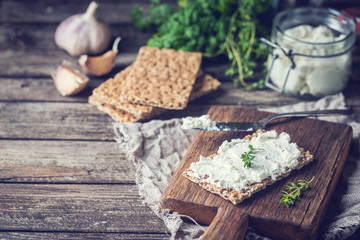 Crispbread toast with homemade herb and garlic cottage cheese on wooden background