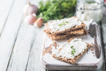 Crispbread toast with homemade herb and garlic cottage cheese on wooden background