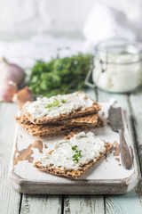Crispbread toast with homemade herb and garlic cottage cheese on wooden background