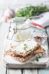 Crispbread toast with homemade herb and garlic cottage cheese on wooden background