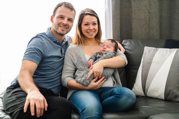 Mother and father with baby having greet time on the sofa at home