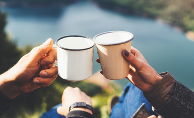 lovers couple hold in hands mug of hot drink, enjoy together of sun flare mountain, travelers drink tea on cup on nature, romantic weekend concept on background of panoramic landscape - Powered by Adobe