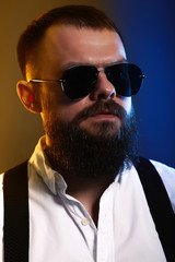 Obraz premium young handsome man with big beard and black sunglasses on black background 