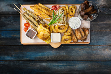 Beer snacks set. Fish set served on cutting board with the mugs, on the wooden background.
