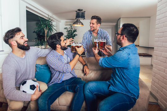 Male friends watching tv and cheering sport games on sofa at home. Group of friends watching american football match.