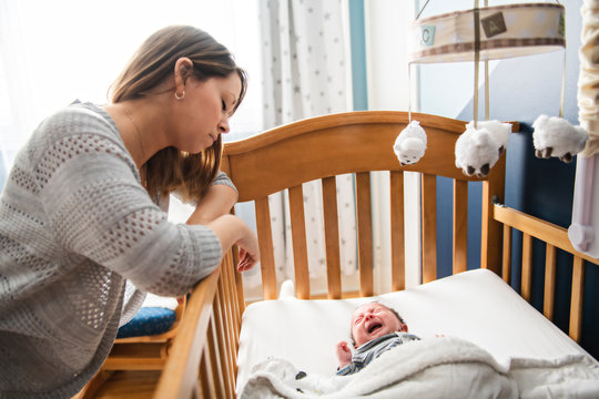 Tired Mother with Upset Baby Suffering with Post Natal Depression.
