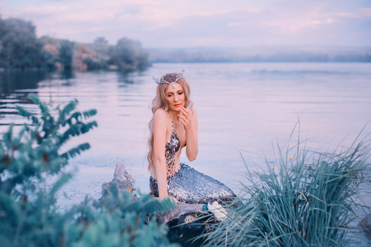 sea queen sadly looks down and thinks for long time,,charming slender blonde lady thoughtfully pondered, art photo in cold tones, mermaid with a long silver tail, image of mythical character