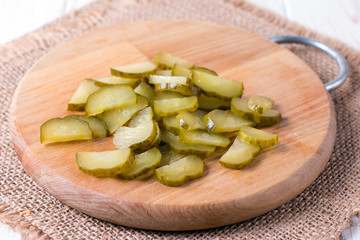 Pickled cucumbers on a wooden board on white background