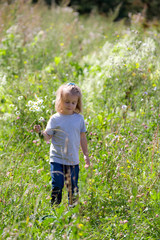 Cute girl on a summer field with a bouquet of daisies