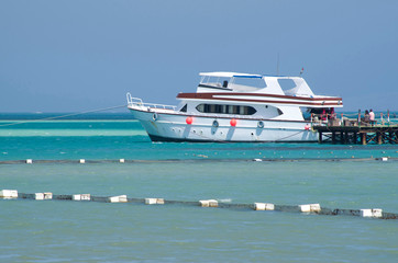 Anchored boat in the sea near the pier and navigational barriers