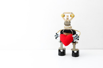 The metal robot holds in hands the heart sewn from fabric. Love. Be my Valentine. St. Valentine's Day. Concept.