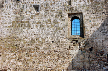 Fototapeta premium Old stone wall built of limestone bricks with a small window wi