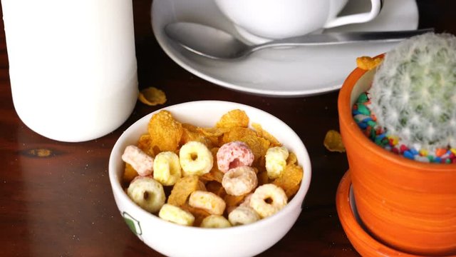 Pour Corn Flakes and Froot Loops to a white bowl for breakfast