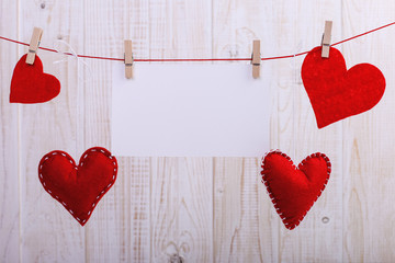 Handmade red felt hearts and white paper hanging on a rope with clothespins. Concept, banner, copy space, form.