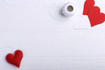 Handmade red felt heart next to threads and a needle on a white table. Women's Day Concept, Copy Space.