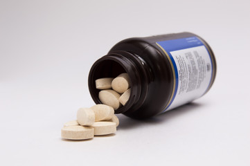a lot of capsule pills spilled out of a jar on a white background