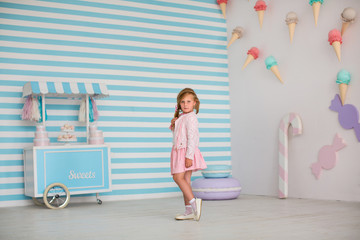 Naklejka premium Happy young girl on background of large candy and ice cream on wall