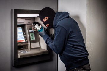 Thief with angle grinder hacks an ATM. Law and crime concept