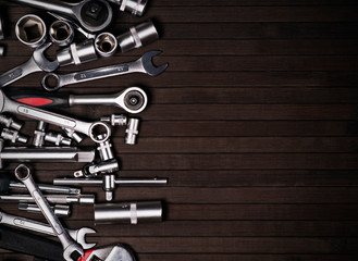 a pile of adjustable and wrench spanners on a black wooden background