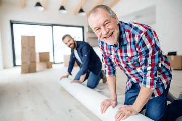 Fototapeta premium A senior man helping his son with furnishing new house, a new home concept.