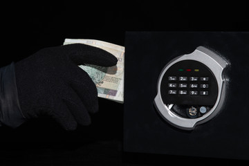 thief stealing valuables from safe at crime scene

