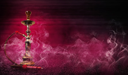 Smoking hookah on the background of an empty wooden wall and concrete floor. Spotlight, red neon light, smoke