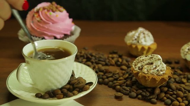 Coffee in white cups, cakes and a scattering of coffee beans on the table. Close-up
