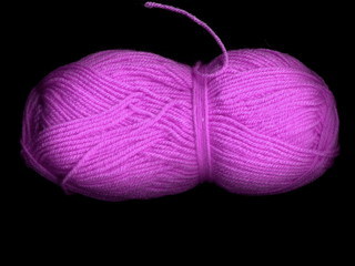 Skein of colored yarn on a dark background.. Skein of purple yarn.