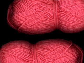 Skein of colored yarn on a dark background. A skein of pink yarn.