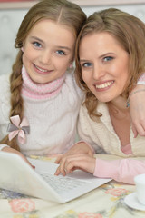 Mother and daughter using laptop together at home
