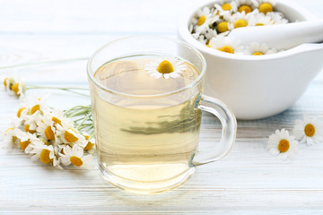 Cup of tea with chamomile flowers on wooden table