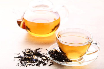 Cup of tea with dry leafs and teapot on wooden table