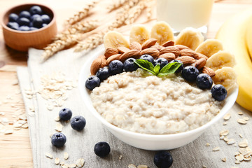 Oatmeal with berries and nuts in bowl on wooden table