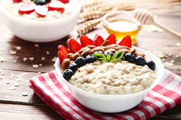 Oatmeal with berries and almonds in bowl on wooden table
