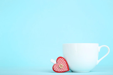 White cup and clothespin with red heart on blue background