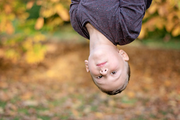 portrait image of pre-school age boy upside down outdoors