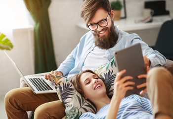 happy couple relaxing at home with laptop and tablet