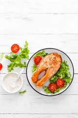 Salmon fish steak grilled and fresh vegetable salad with tomato and lettuce. Healthy food. Top view