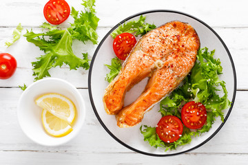 Salmon fish steak grilled and fresh vegetable salad with tomato and lettuce. Healthy food. Top view