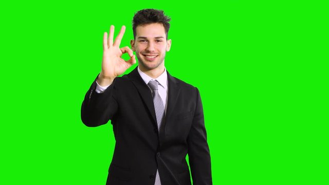 Smiling young man showing thumbs up isolated on green screen chroma key background