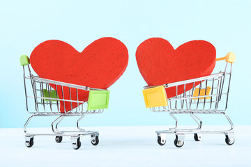 Shopping carts with red hearts on wooden table