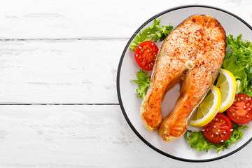 Salmon fish steak grilled and fresh vegetable salad with tomato and lettuce. Healthy food. Top view